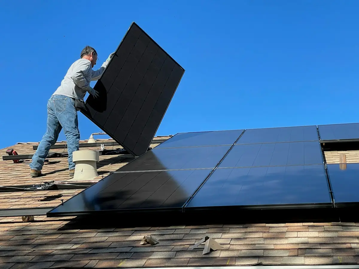 Instalador fixando painel solar em telhado