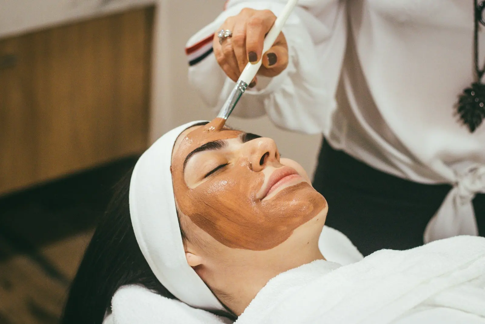 Cliente recebendo tratamento facial com máscara em spa