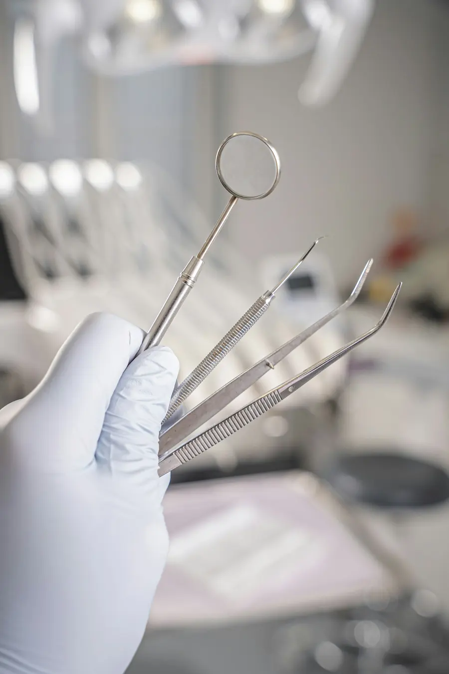 Mão com luva segurando instrumentos odontológicos esterilizados