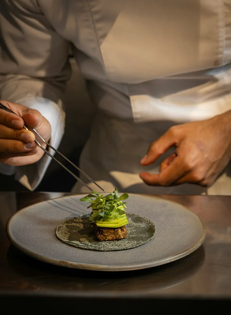 Chef finalizando um prato com folhas frescas
